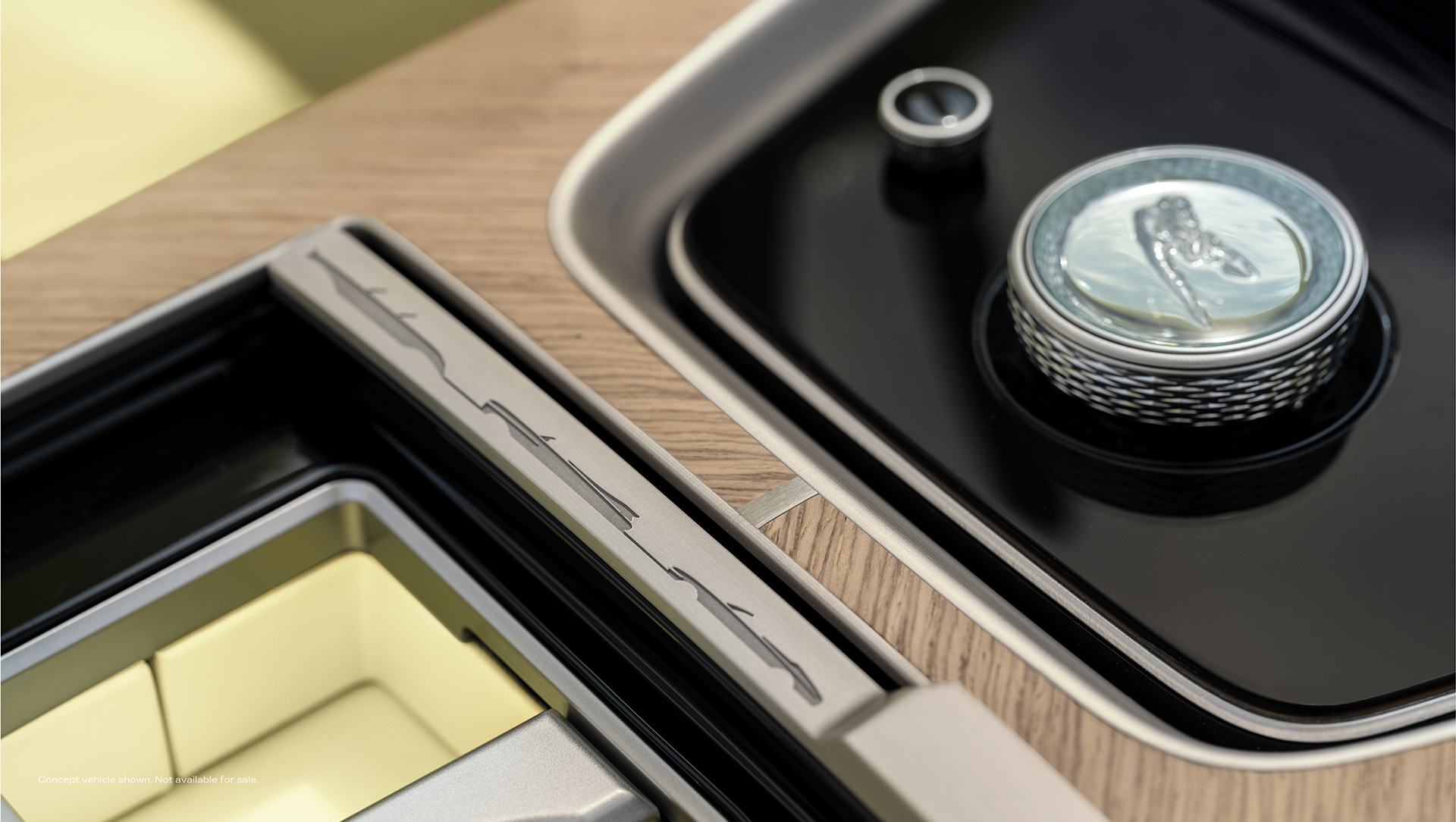 Close up view of the crystal multi-functional controller with Cadillac Goddess emblem in the Cadillac SOLLEI and front console cupholder door accent featuring Cadillac’s historical vehicle silhouettes